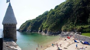 Une plage avec une tour en pierre, une eau cristalline et une végétation luxuriante.