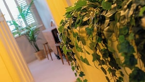 Un pasillo con pared verde de plantas, suelo alfombrado y una puerta que da a otra habitación.