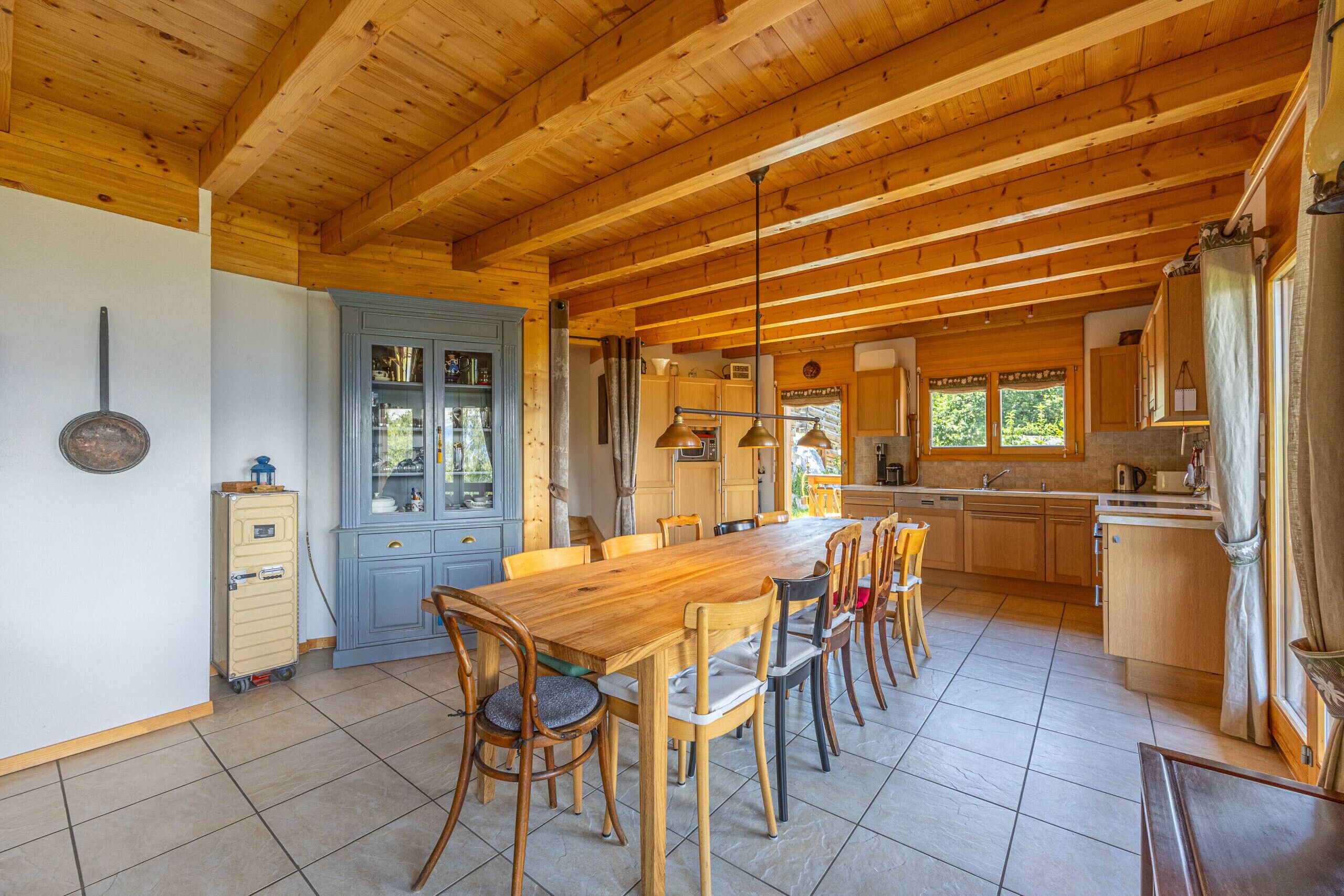 A spacious kitchen with wooden cabinets, a large dining table, and a blue door.