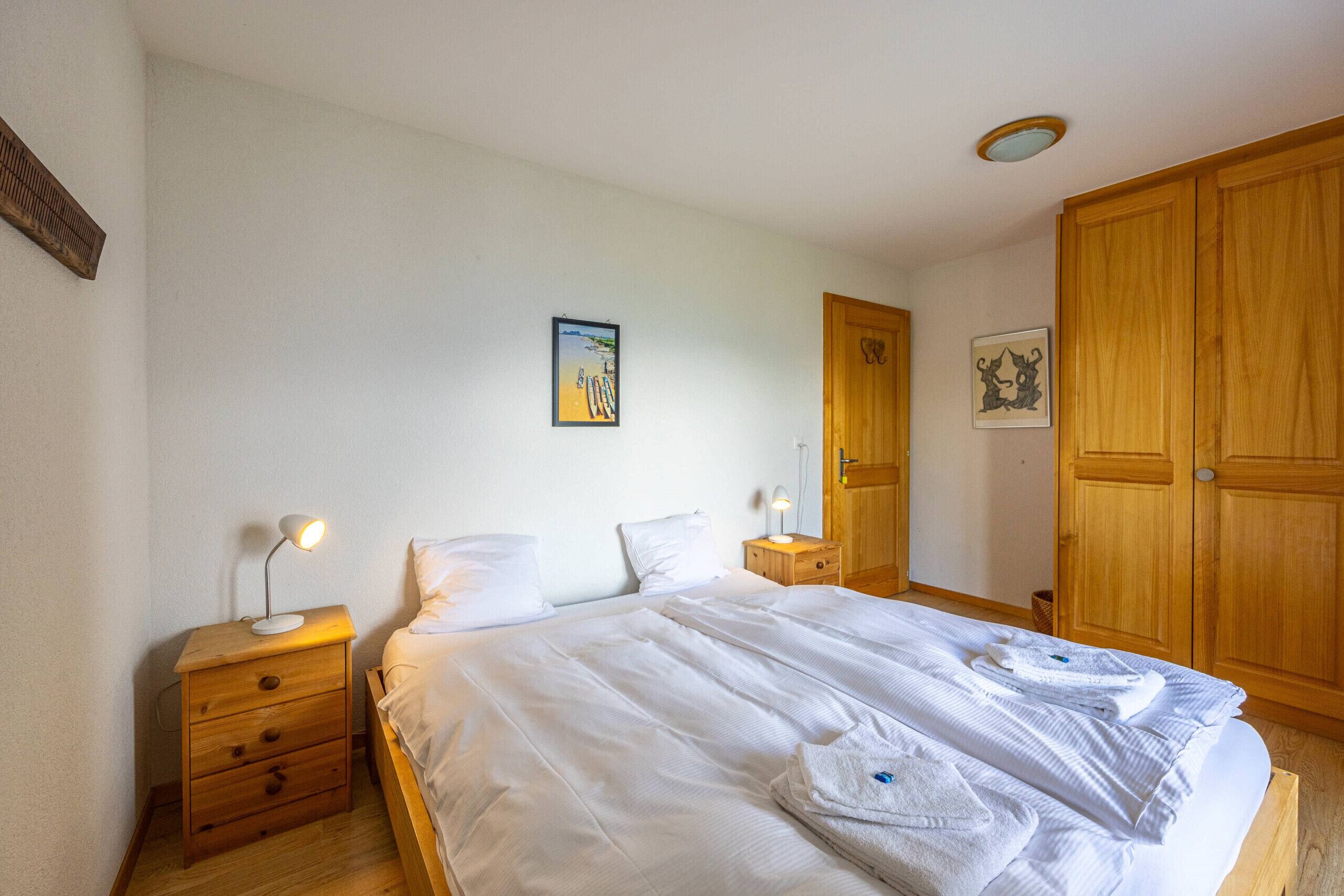 A bedroom with a large bed, wooden nightstands, and a wardrobe.