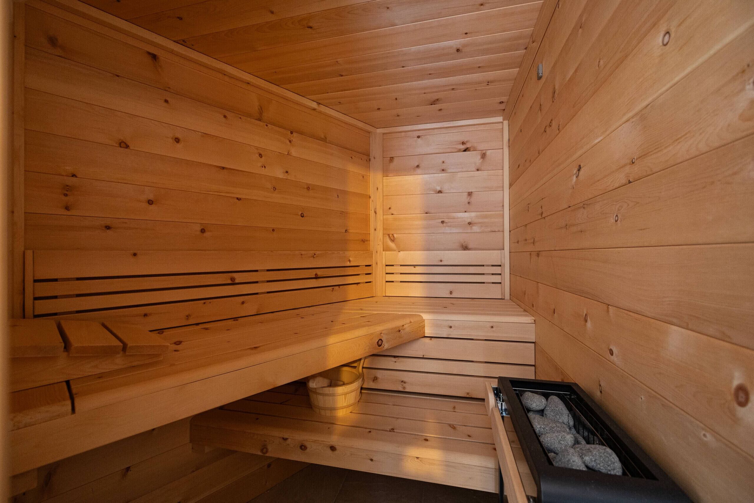 A wooden sauna with benches and a stone-filled container.