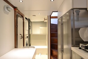 A narrow hallway with a white countertop, a stainless steel refrigerator, and a wooden staircase. - Dvi Marije (Palermo)