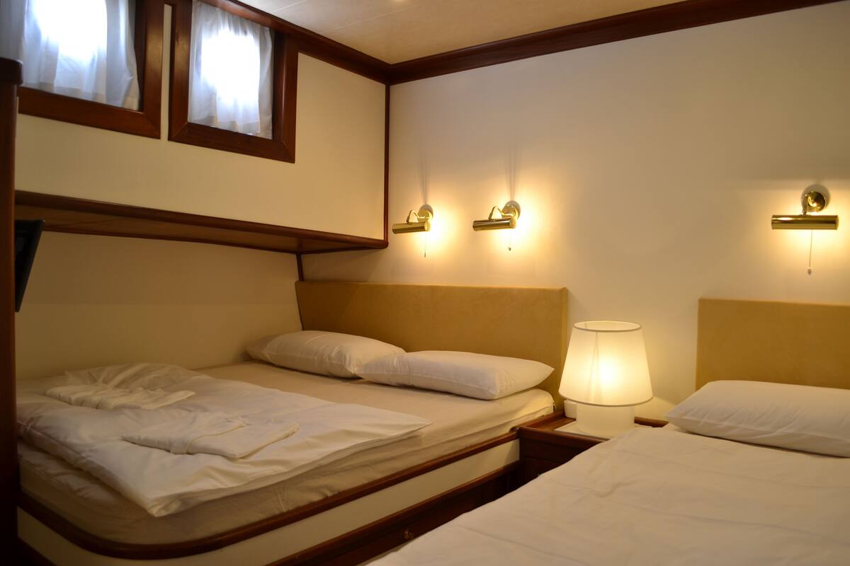 A hotel room with two beds, wooden headboards, and wall-mounted lamps.