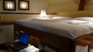 Ett hotellrum med en säng, ett skrivbord med en bärbar dator och en lampa.