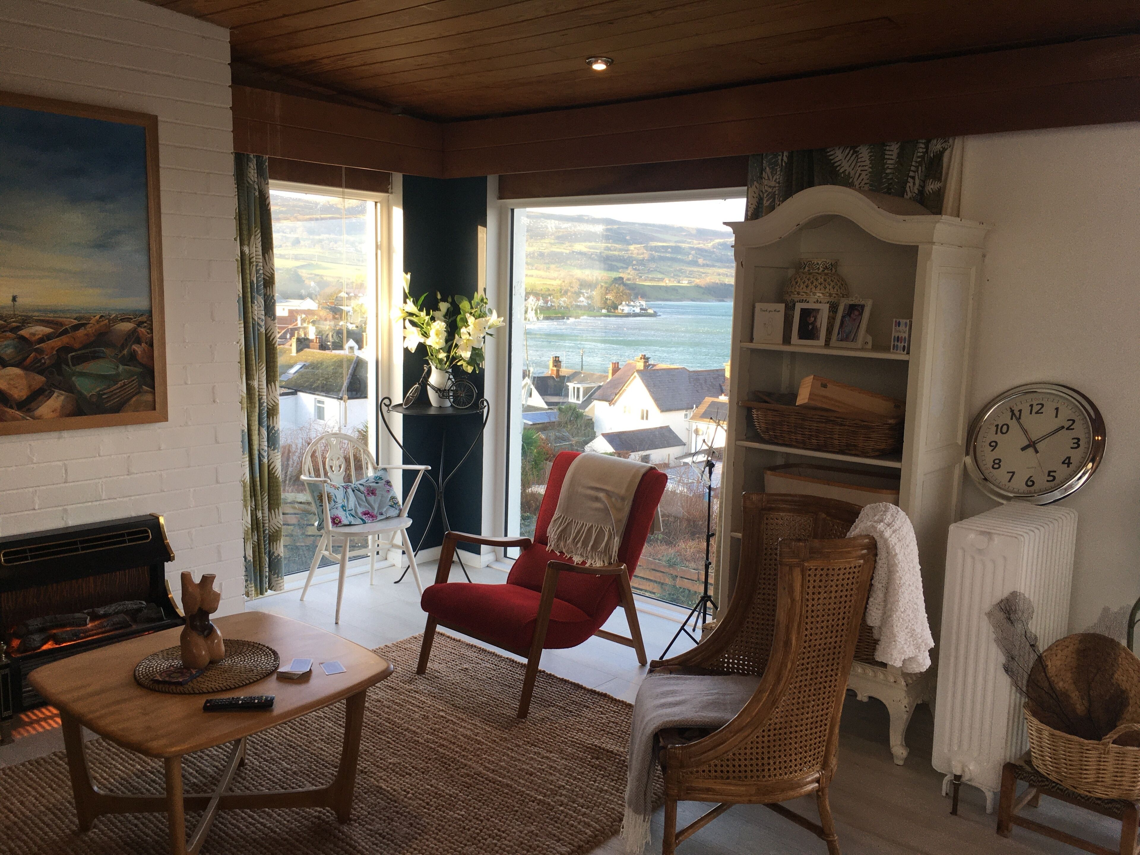 Un soggiorno accogliente con camino, un tavolo da pranzo e vista mare attraverso ampie finestre.
