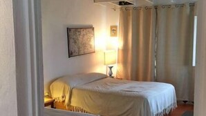 A room with two beds, a ceiling fan, a lamp, and a window with curtains. - SUITES LAM BEACH HOUSE Panoramic views. (Actopan)
