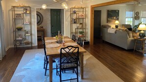 Zona pranzo con tavolo e sedie in legno, circondata da mensole con oggetti decorativi.
