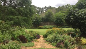 Un giardino con diverse piante e un vialetto in pietra che conduce a un prato.