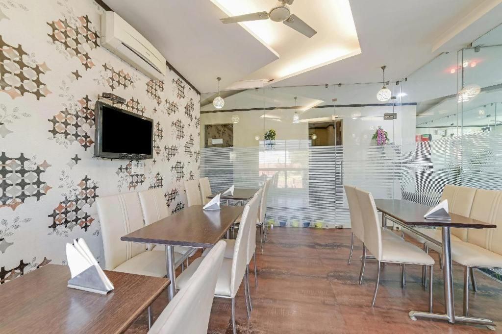 Un comedor moderno con una mesa larga, sillas, un televisor y papel tapiz estampado.
