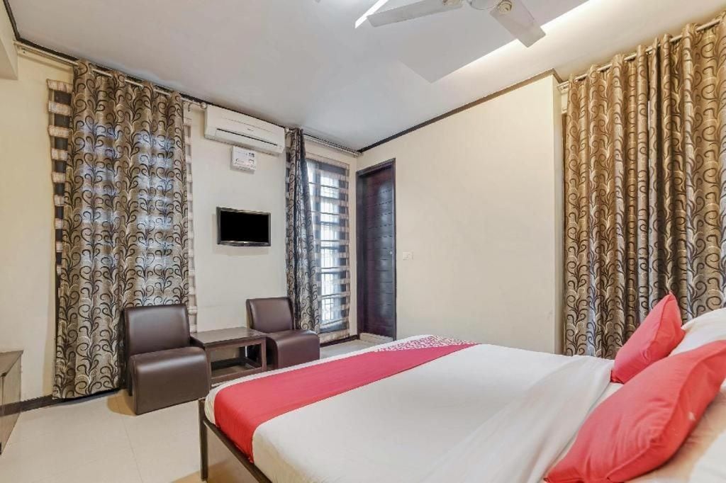 Una camera d'albergo con un letto, una scrivania, due sedie, un televisore e tende.