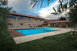 A pool area with stone walls, lounge chairs, and a covered seating area. - Quinta do Olival (Chaves)