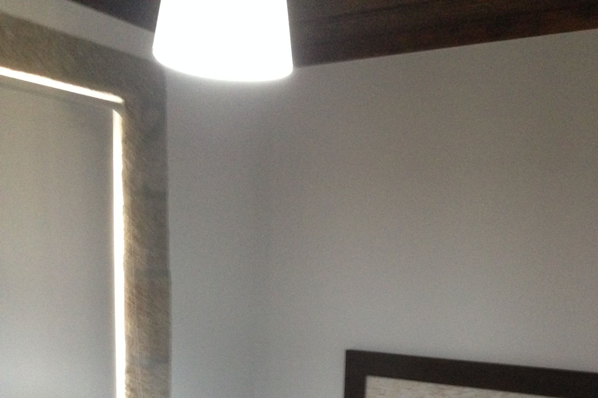A single bed with a wooden headboard in a room with a sloped ceiling and a visible window.