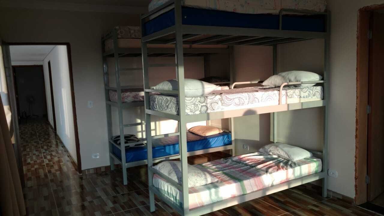 Habitación con literas, una colcha estampada, un caja de almacenamiento azul y una puerta visible.