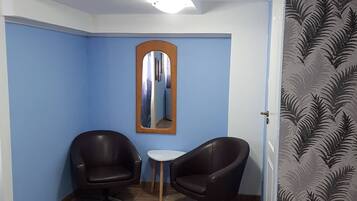 Una habitación con dos sillones de cuero negro, una mesita blanca y un espejo en la pared.