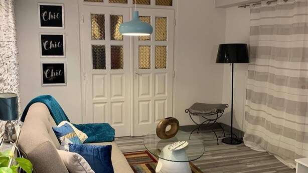 A modern living room with a sofa, ottomans, a glass coffee table, and a lamp. - Airport16 B&B (Vecsés)