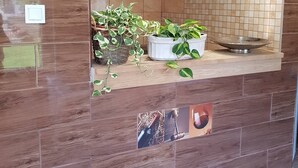 A reception area with a wooden reception desk, a clock, and a tiled wall with framed pictures. - Airport16 B&B (Vecsés)
