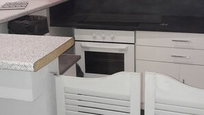 Una cocina con extractor de acero inoxidable, armarios blancos y encimera negra.