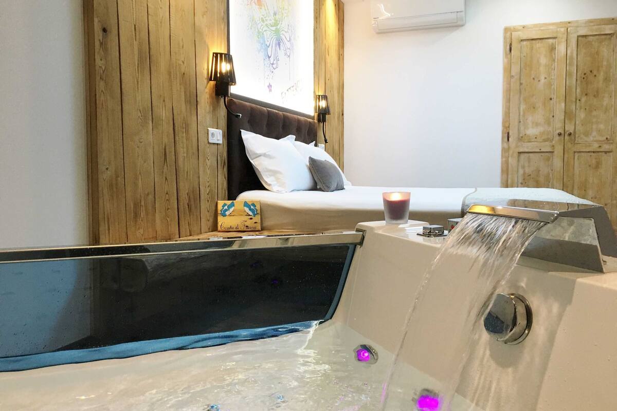 A bedroom with a bed, a wooden wall, a nightstand, a candle, and a water feature.