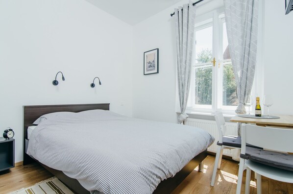 A neatly arranged bedroom with a bed, bedside table, lamp, and a window with curtains.