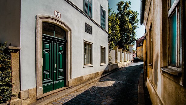 A narrow cobblestone street flanked by historic buildings with green doors and shutters. - Old Town Tale Apartments (Zagreb)
