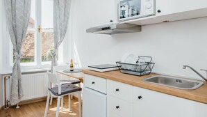 A modern kitchen with white cabinets, a wooden countertop, a built-in microwave, and a stainless steel sink. - Old Town Tale Apartments (Zagreb)