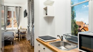 A compact kitchen with a wooden countertop, a stainless steel sink, a microwave, and a small dining area with a table and chairs. - Old Town Tale Apartments (Zagreb)