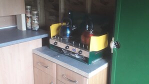 A compact kitchen with a stove, two kettles, and a green refrigerator. - Rosie Traditional Gypsy Wagon (Rhayader)