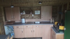 A compact kitchen with wooden cabinets, a sink, and a stove. - Rosie Traditional Gypsy Wagon (Rhayader)