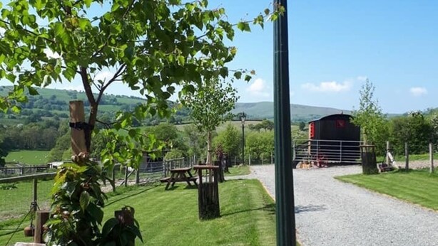 A rural pathway with a lamppost, picnic tables, and a view of a farmstead in the distance. - Rosie Traditional Gypsy Wagon (Rhayader)
