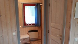 Une pièce avec un plancher en bois, un lit, une fenêtre avec des rideaux et une porte.