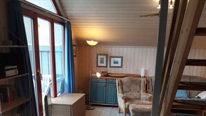 Une pièce chaleureuse avec une table en bois, des chaises, un canapé et un escalier.