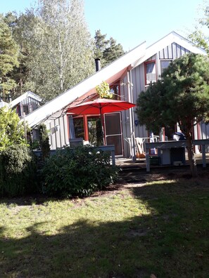 A house with a red umbrella, a small porch, and a garden. - Comfortable holiday home with sauna (Mirow)