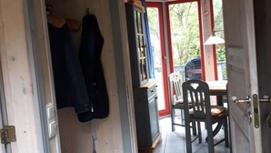 Une pièce avec un plancher en bois, une table entourée de chaises, un meuble et une porte donnant sur l’extérieur.