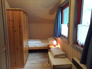 A small, cozy room with a single bed, a nightstand with a lamp, and a wooden wardrobe. - Comfortable holiday home with sauna (Mirow)