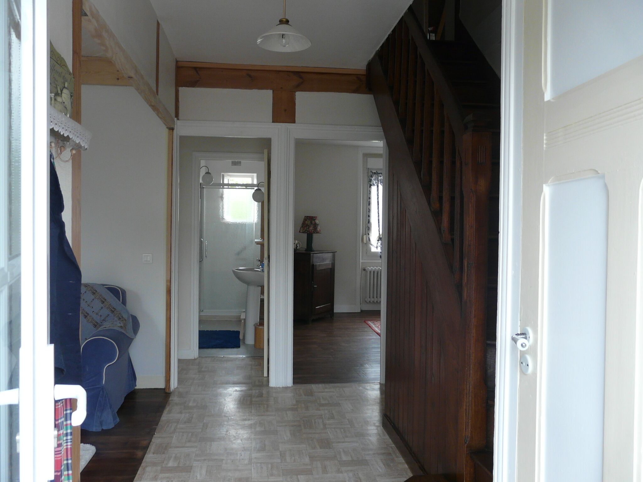 Passadís amb terra de fusta, una porta blanca i una escala que condueix a una altra habitació.