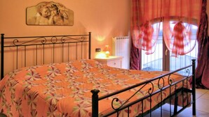 A bedroom with a bed, a nightstand, a lamp, a window with curtains, and a wall-mounted picture. - Autumn Apartment (Agriturismo Il Melograno) (Venezia)