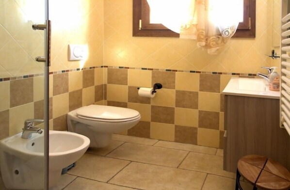 A bathroom with a toilet, bidet, sink, and a mirror.