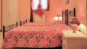 A bedroom with a bed, a nightstand, a lamp, a wardrobe, and a window with curtains. - Autumn Apartment (Agriturismo Il Melograno) (Venezia)