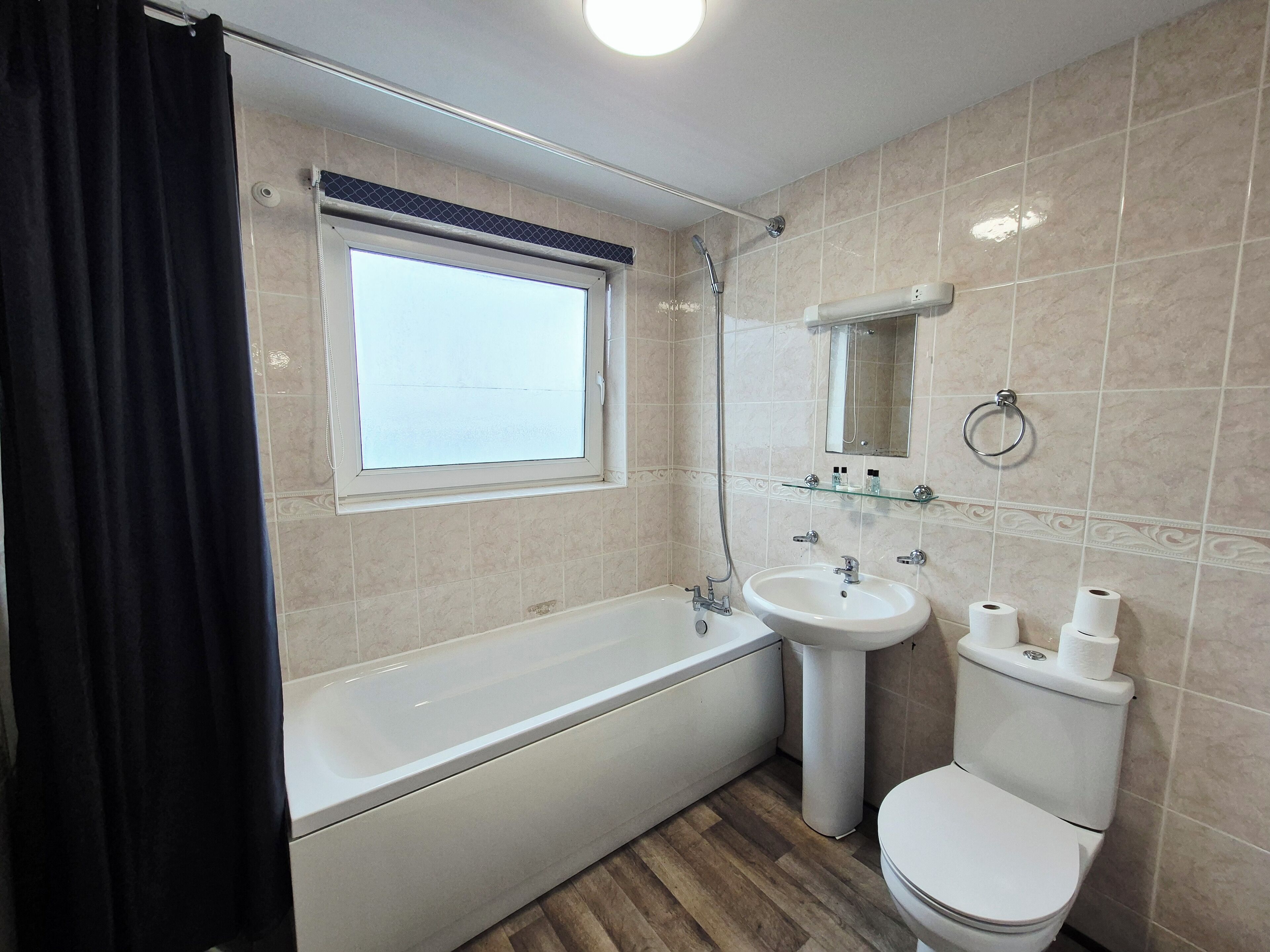 Een badkamer met een bad, wastafel, toilet en een raam.