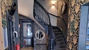 A wooden-floored hallway with a black staircase and ornate wall designs. - OYO Ivy Hotel (Skegness)