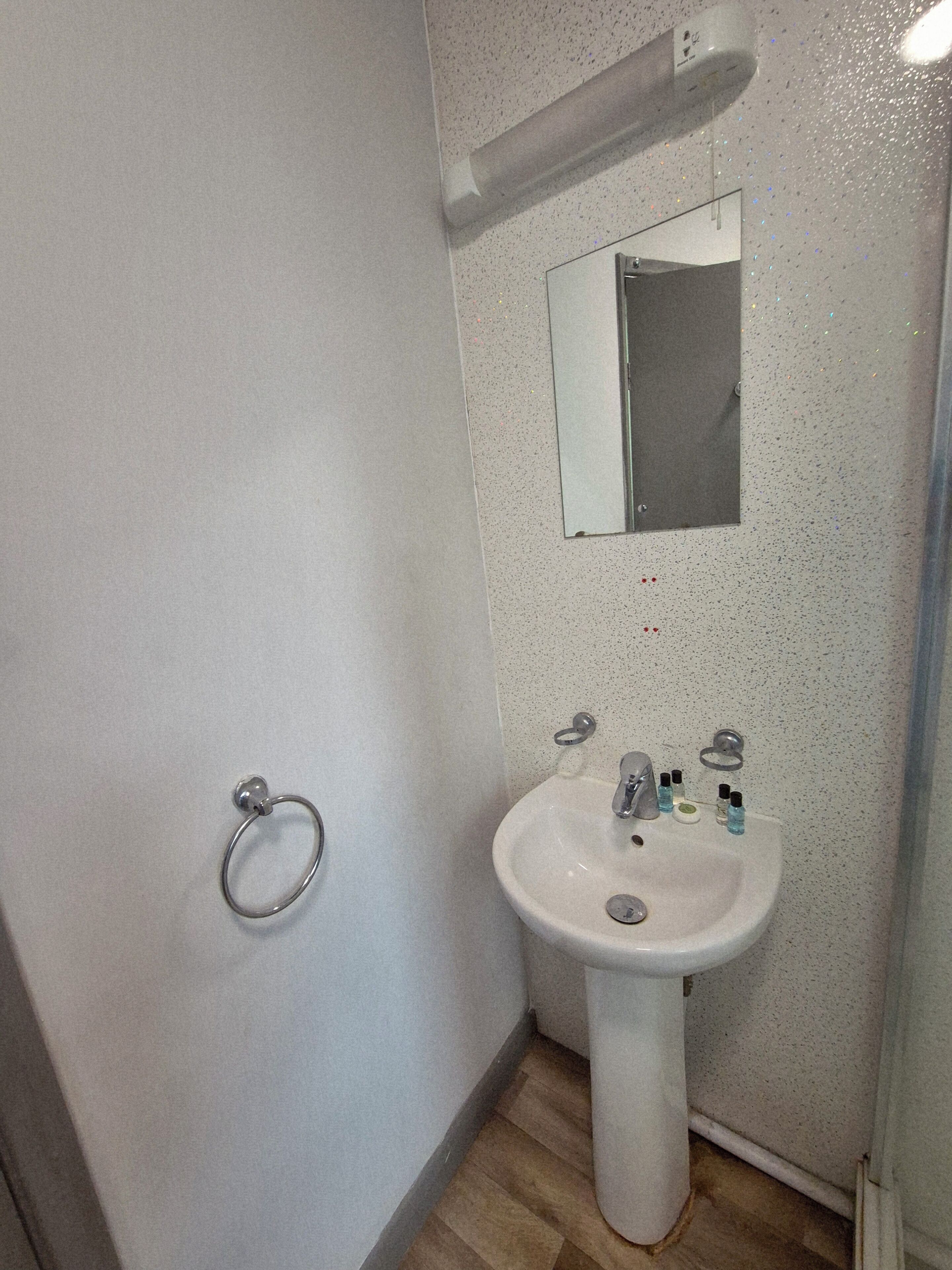 Une salle de bain avec un lavabo blanc, un miroir et un porte-serviettes.