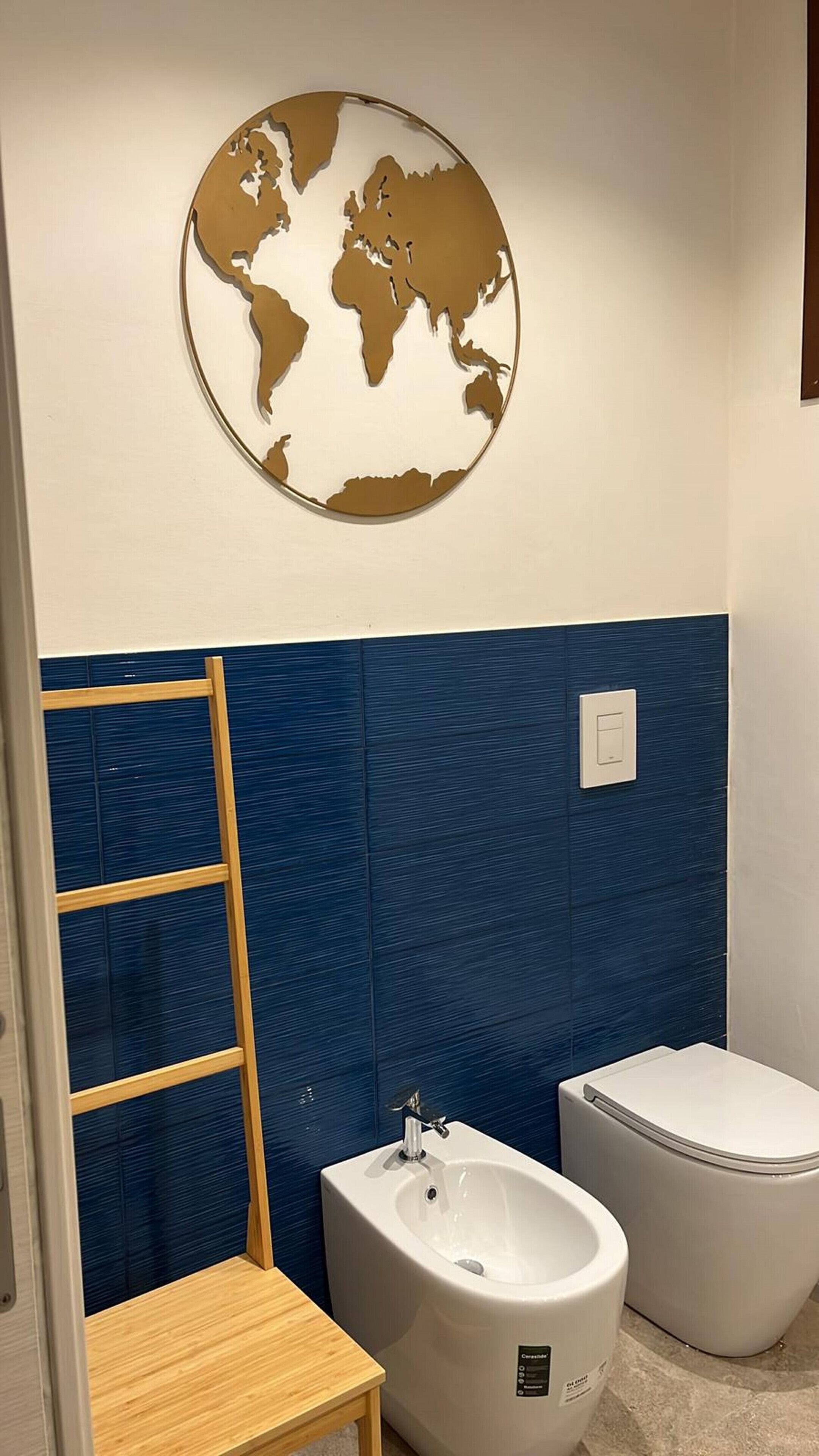 A bathroom with a globe decoration, a bidet, a toilet, and a wooden stool.