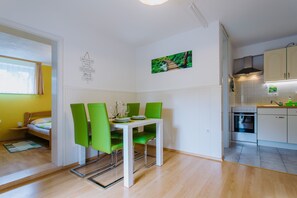 A compact kitchen with a dining area, a bed, and a small window.