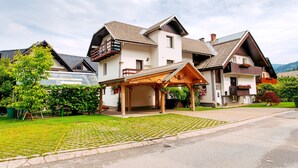 A two-story house with a covered porch, a garage, and a well-maintained lawn. - Apartments Green Paradise D&S (Bohinj)