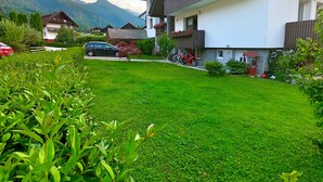 A residential area with a well-maintained lawn, a parked car, and a building with balconies. - Apartments Green Paradise D&S (Bohinj)