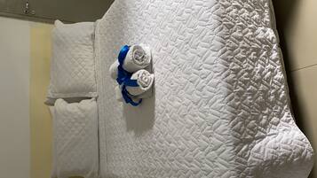 Un lit blanc matelassé, orné d’un ruban bleu noué autour de la tête de lit.
