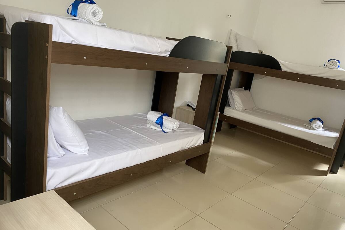 Um quarto com três beliches, cada um com uma almofada e uma toalha enrolada.