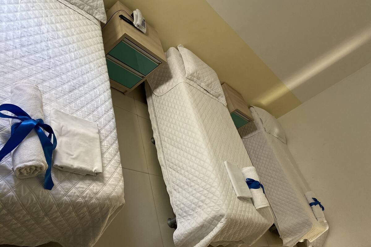 Quarto de hotel com cama, mesa de cabeceira e telefone.