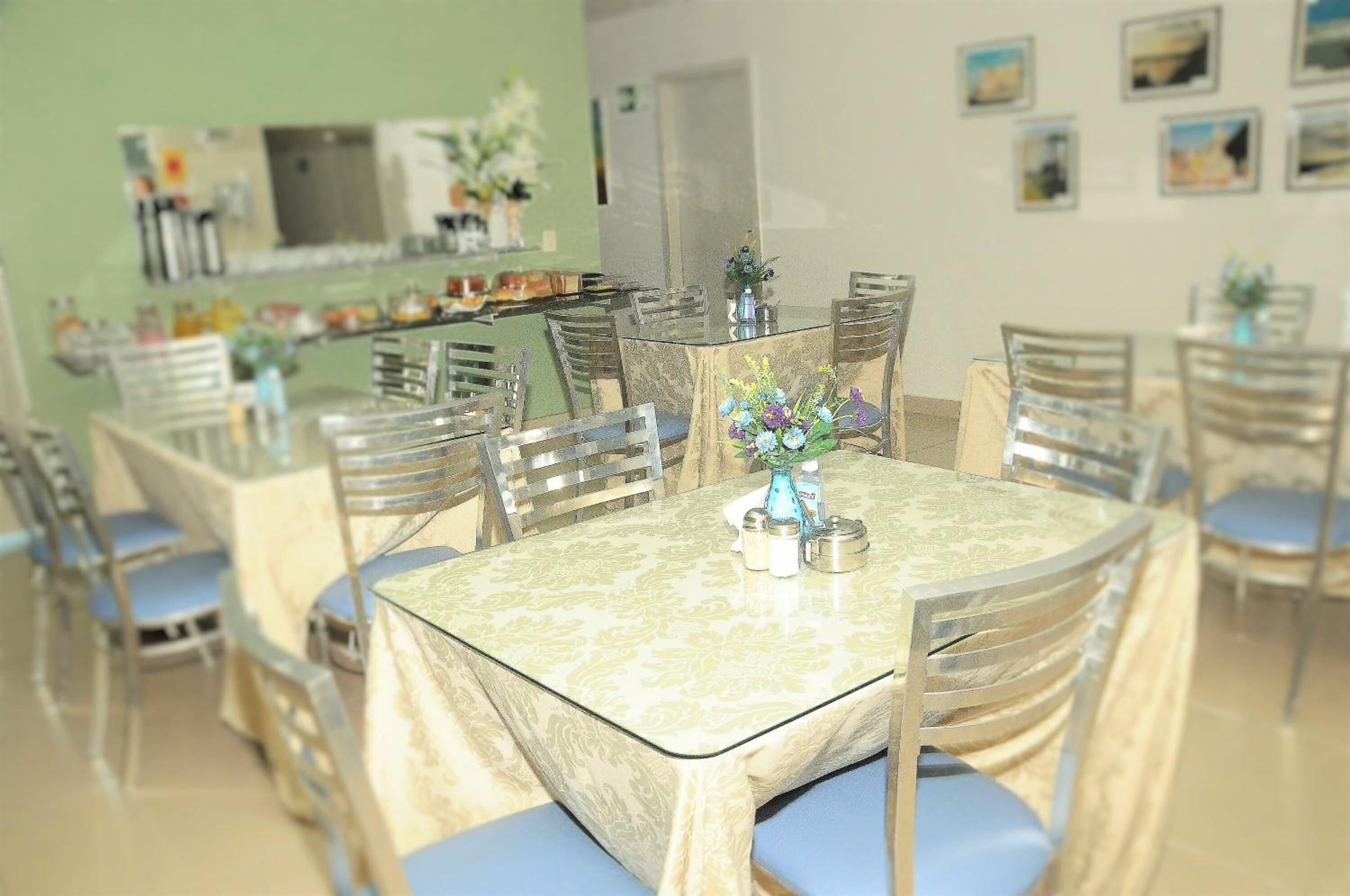Un comedor con una mesa redonda, sillas y un jarrón con flores.