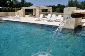 Una piscina al aire libre, sombrillas, sillones reclinables de piscina
